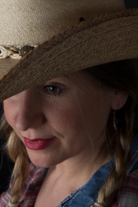Close up photographic portrait of blonde model in plaits wearing cowboy hat