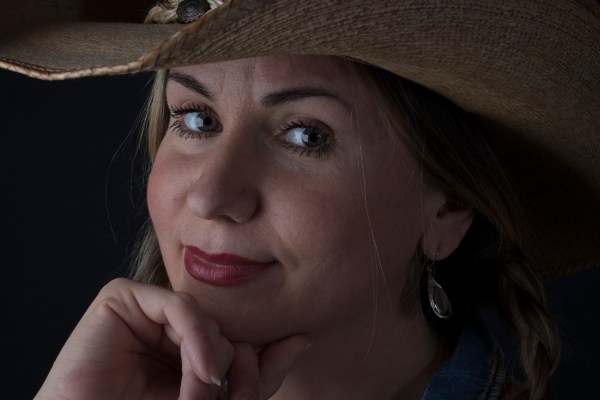 Close up photographic portrait of blonde model, hair in plaits, wearing cowboy hat
