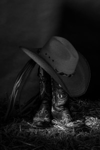 Black and white still life photograph of cowboy boots and hat